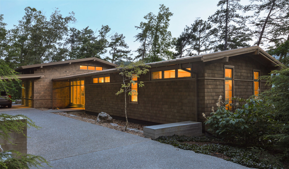 Пример оригинального дизайна: двухэтажный, деревянный, коричневый частный загородный дом среднего размера в стиле модернизм с двускатной крышей