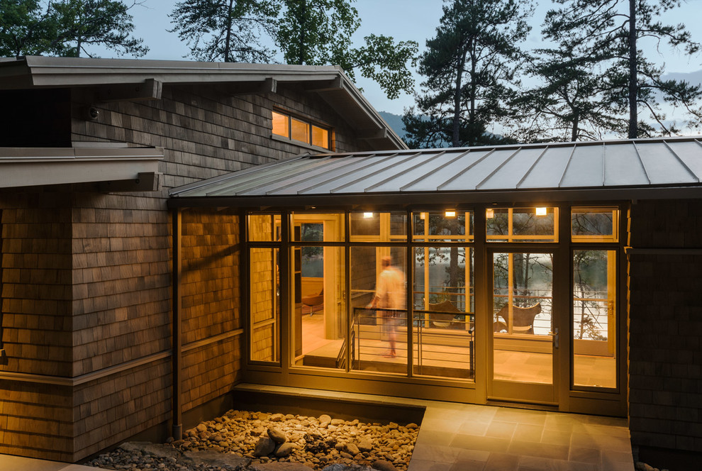 Modelo de fachada de casa marrón moderna de tamaño medio de dos plantas con revestimiento de madera, tejado a dos aguas y tejado de metal