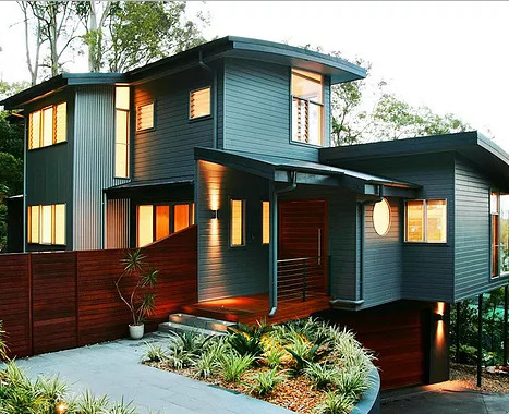 Modelo de fachada de casa multicolor actual de tamaño medio a niveles con revestimiento de aglomerado de cemento, tejado a dos aguas y tejado de metal