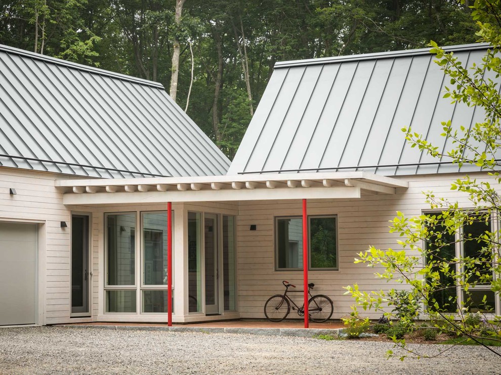 Exemple d'une façade de maison beige nature en bois de plain-pied avec un toit à deux pans et un toit en métal.