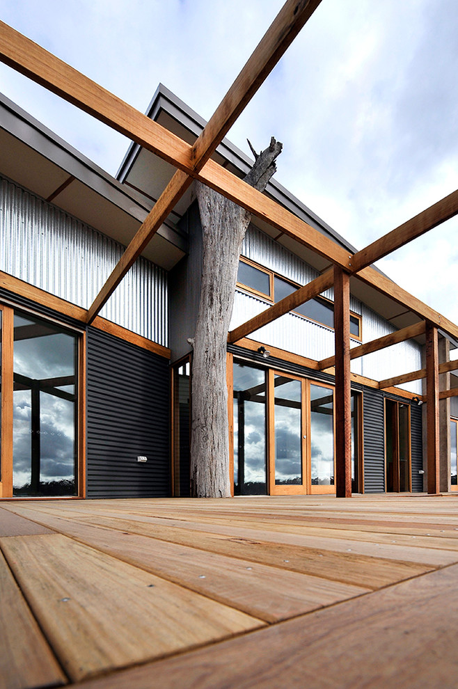 На фото: одноэтажный, серый дом в современном стиле с облицовкой из металла и плоской крышей с