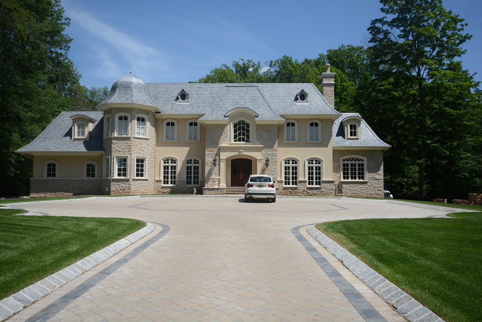 Пример оригинального дизайна: большой, двухэтажный, бежевый частный загородный дом в классическом стиле с облицовкой из цементной штукатурки и вальмовой крышей
