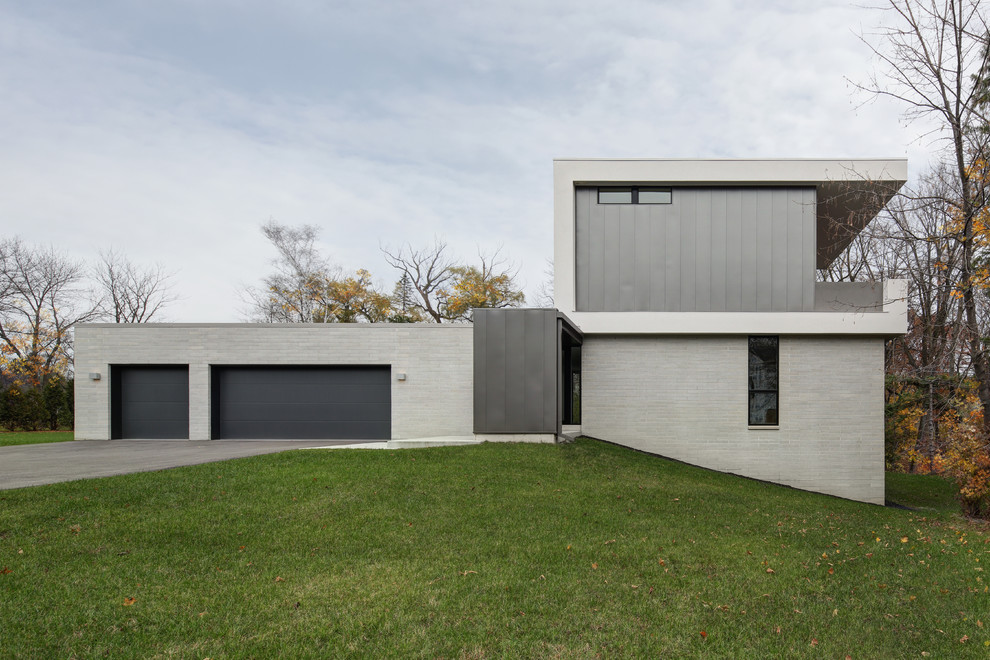 Пример оригинального дизайна: двухэтажный, серый частный загородный дом в стиле модернизм с комбинированной облицовкой и плоской крышей
