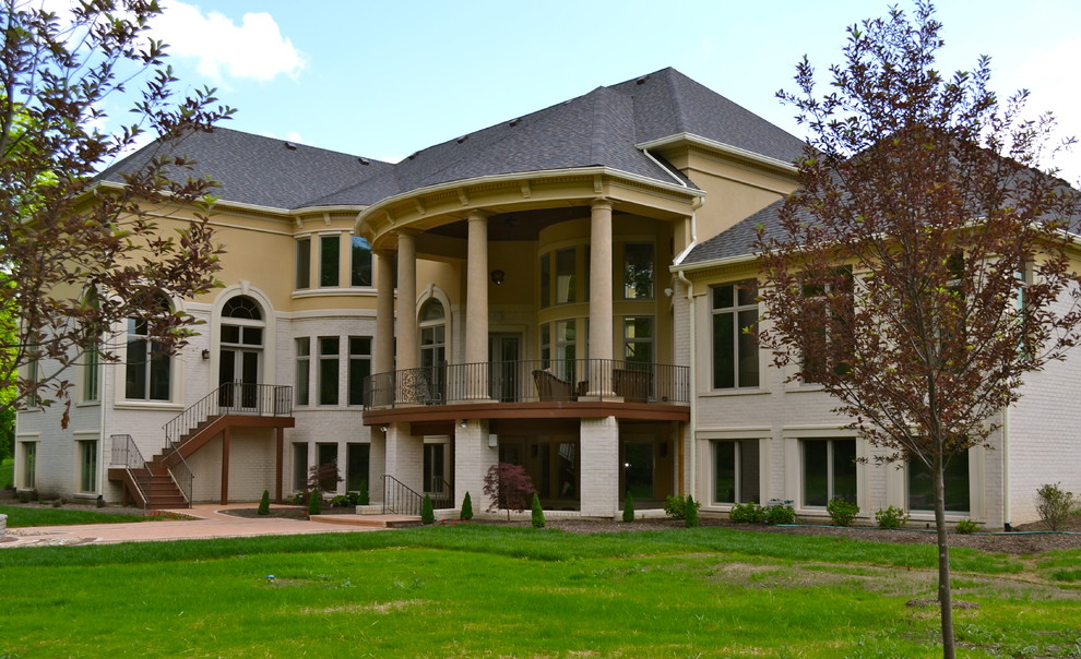 Пример оригинального дизайна: большой, двухэтажный, бежевый дом в классическом стиле с облицовкой из цементной штукатурки и двускатной крышей