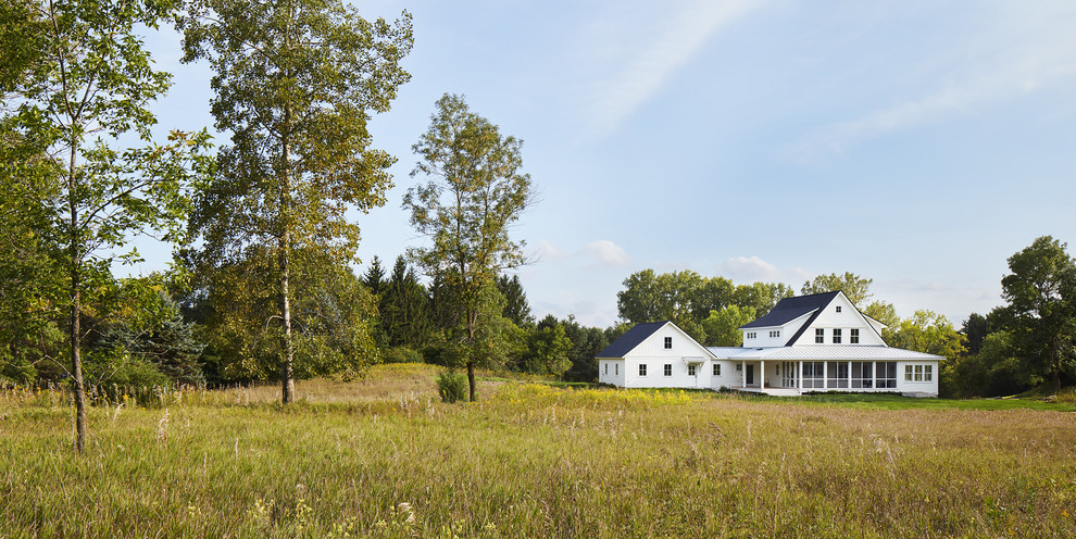 Diseño de fachada blanca de estilo de casa de campo de tamaño medio de dos plantas con revestimiento de aglomerado de cemento y tejado a dos aguas