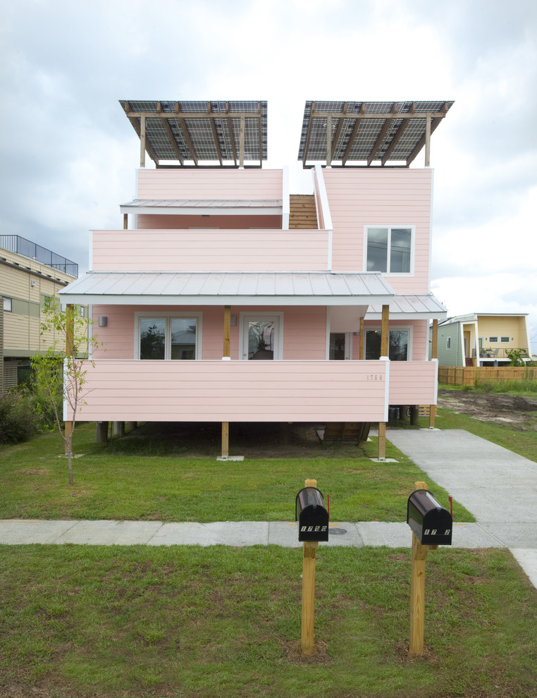 Contemporary two floor house exterior in New Orleans with wood cladding and a pink house.