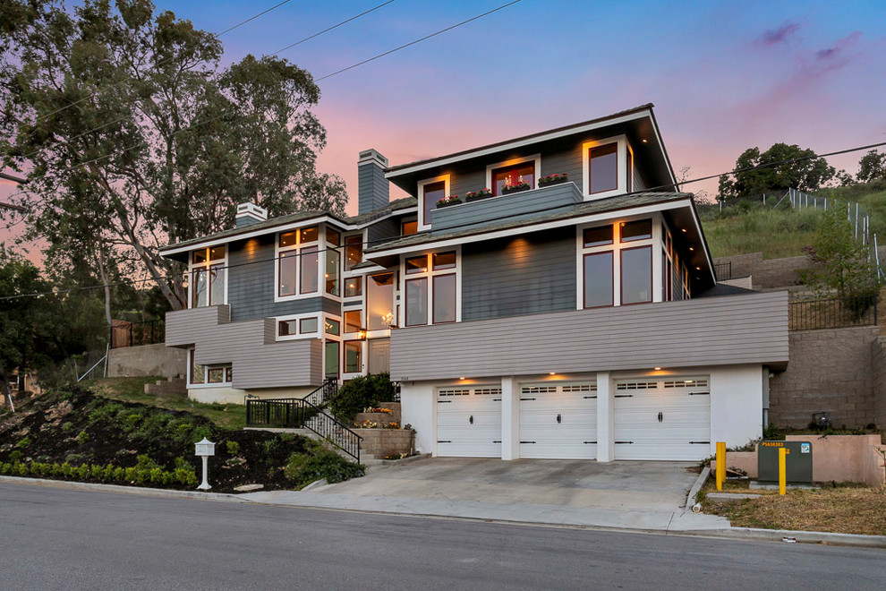 Large mid-century modern gray split-level mixed siding exterior home photo in Los Angeles with a tile roof