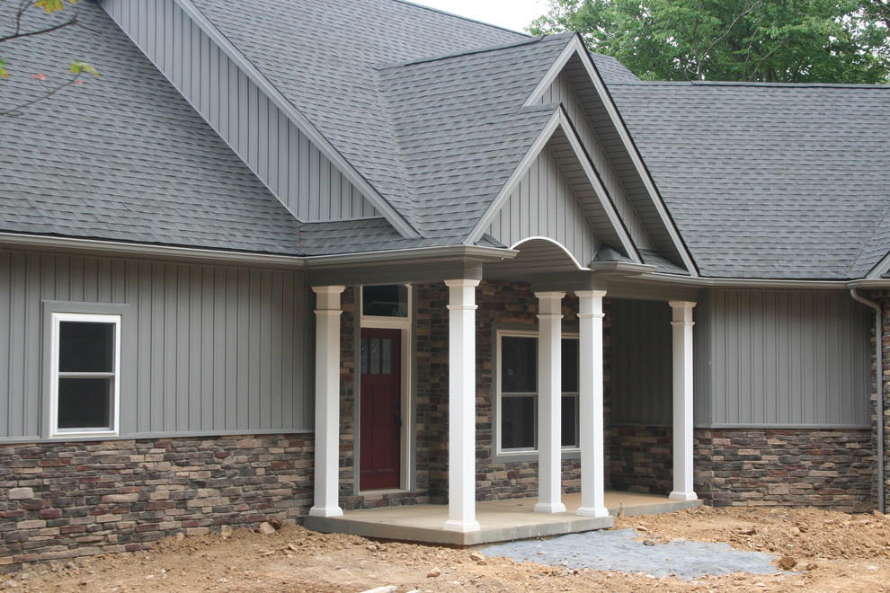 Réalisation d'une grande façade de maison grise craftsman en pierre de plain-pied avec un toit à quatre pans et un toit en shingle.