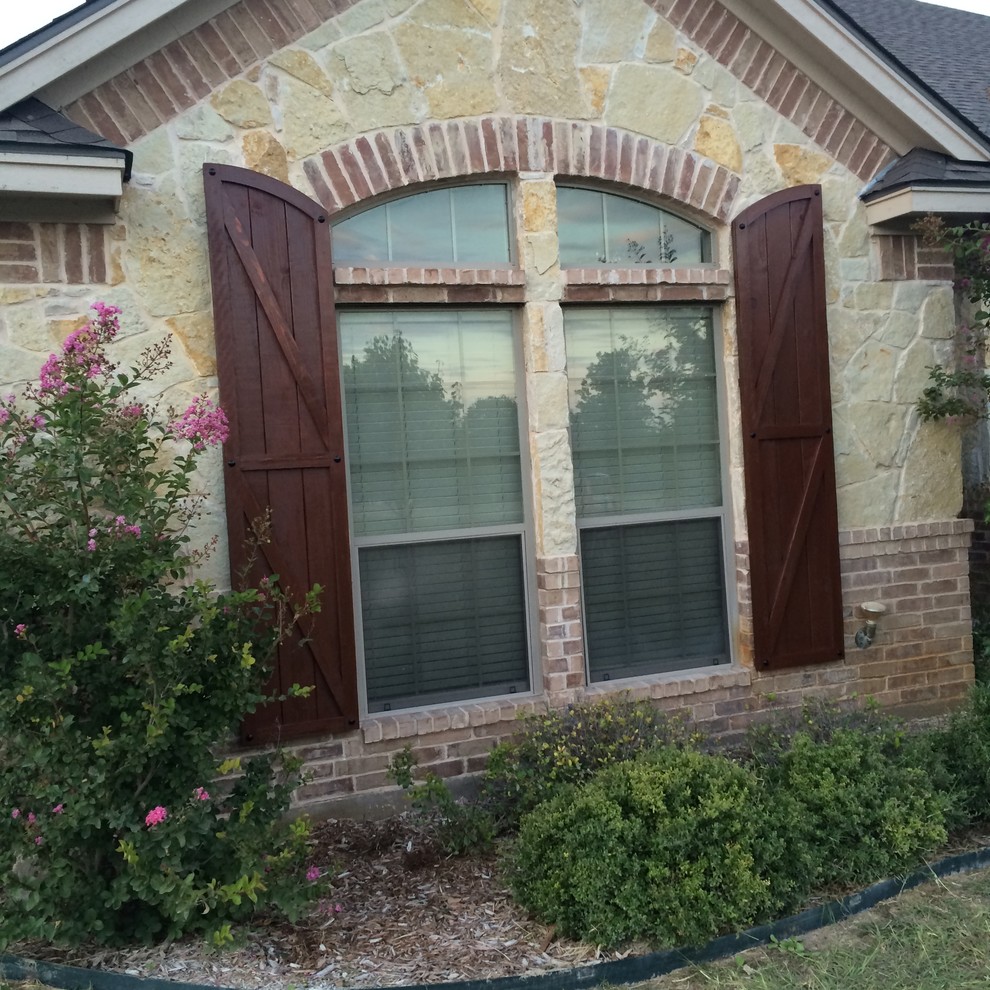 Design ideas for a large and beige rustic bungalow house exterior in Dallas with stone cladding.