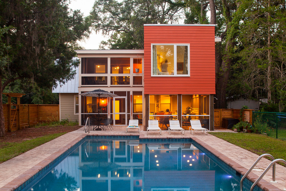На фото: двухэтажный, красный дом среднего размера в стиле ретро с облицовкой из ЦСП и мансардной крышей