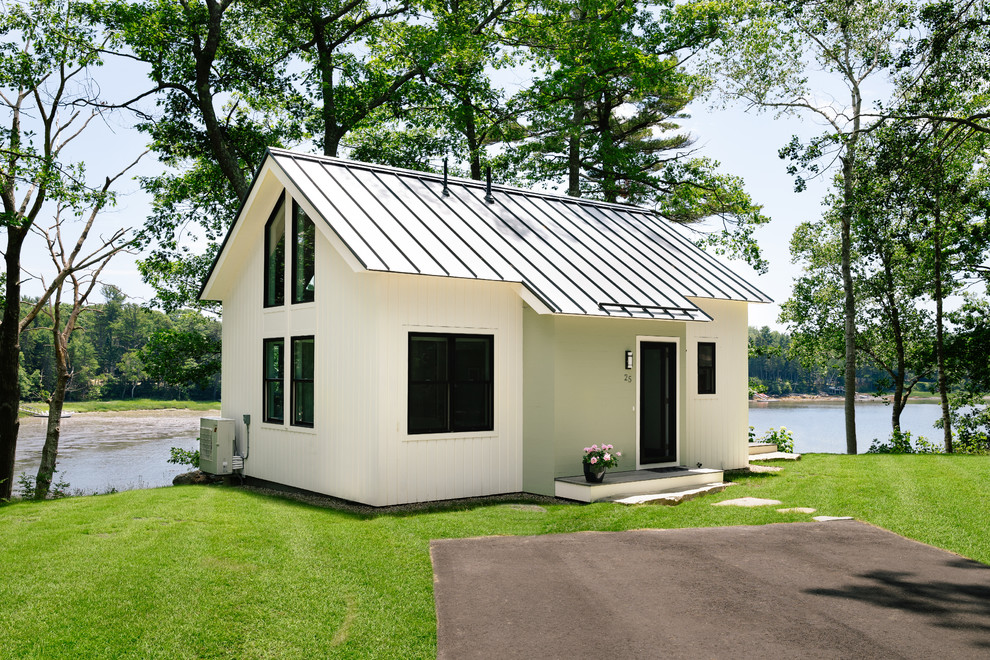 Immagine della villa piccola bianca country a due piani con copertura in metallo o lamiera e tetto a capanna