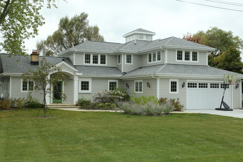 Réalisation d'une grande façade de maison grise marine en panneau de béton fibré à un étage avec un toit à quatre pans et un toit en shingle.