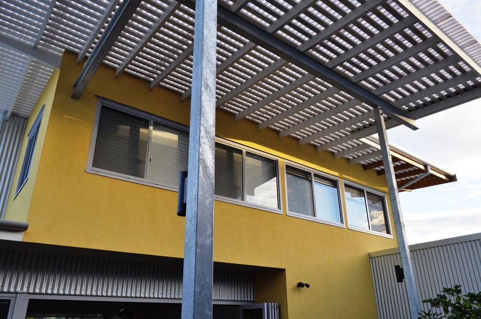 Modelo de fachada amarilla actual de tamaño medio de dos plantas con revestimiento de metal y tejado plano