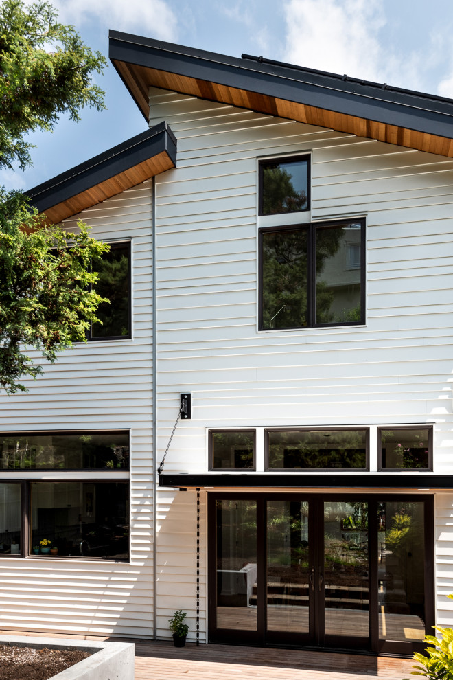 Réalisation d'une grande façade de maison blanche design en bois à deux étages et plus avec un toit en appentis et un toit en métal.