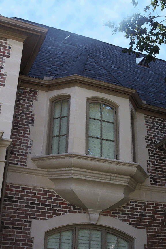 Esempio della villa ampia beige classica a due piani con rivestimento in stucco e copertura in tegole