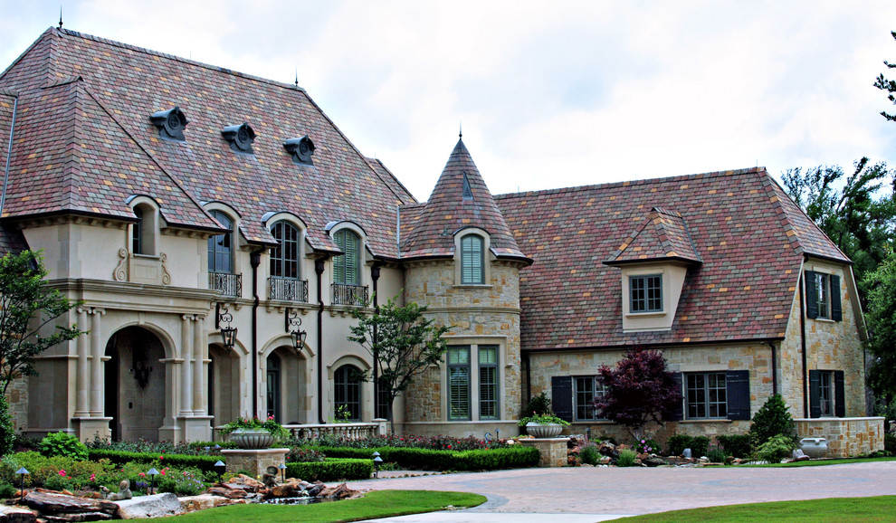 На фото: двухэтажный, огромный, бежевый частный загородный дом в классическом стиле с облицовкой из цементной штукатурки и черепичной крышей с