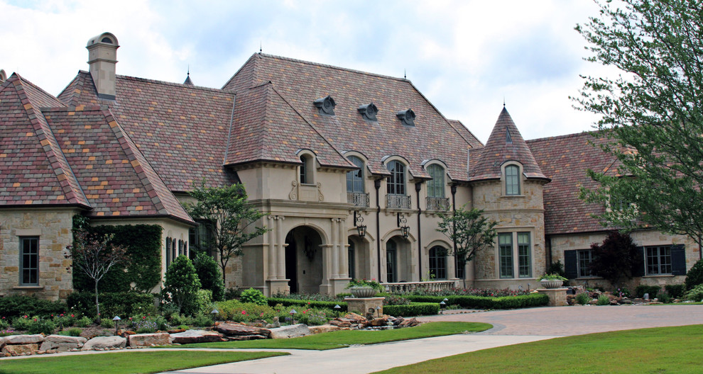 Пример оригинального дизайна: двухэтажный, огромный, бежевый частный загородный дом в классическом стиле с облицовкой из цементной штукатурки и черепичной крышей