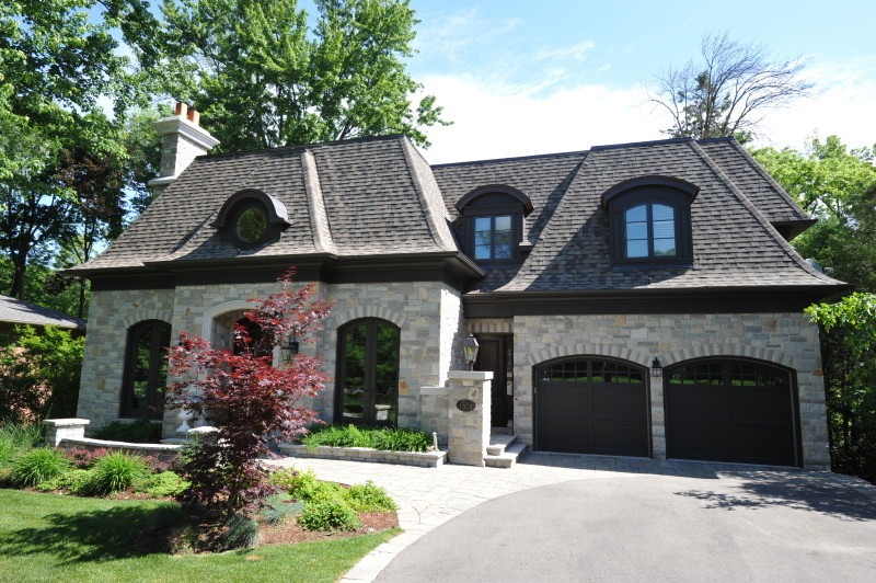 Cette image montre une grande façade de maison beige traditionnelle en pierre à un étage avec un toit à quatre pans et un toit en shingle.