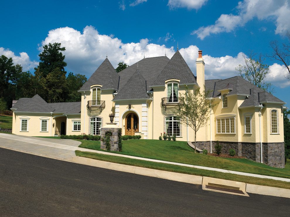 Example of a large classic yellow two-story stucco house exterior design in Other with a shingle roof