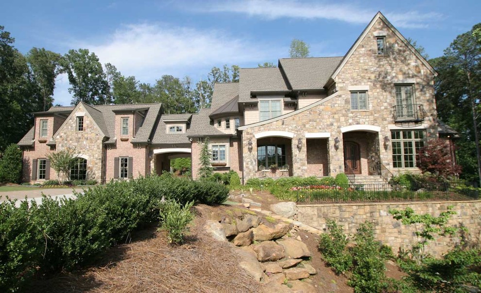 Large traditional beige three-story stone exterior home idea in Atlanta