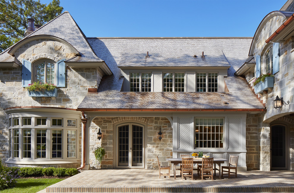 Inspiration pour une grande façade de maison multicolore en pierre à un étage avec un toit à quatre pans et un toit en shingle.