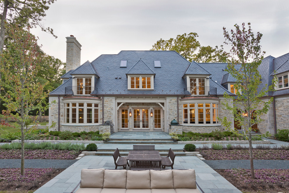 Design ideas for a beige traditional house exterior in Chicago with three floors, stone cladding and a hip roof.