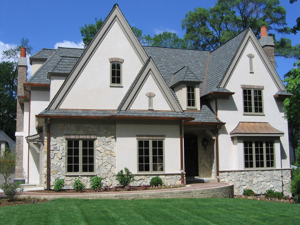 Inspiration for a large timeless beige three-story stucco gable roof remodel in Other