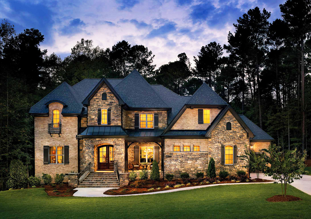 Cette photo montre une grande façade de maison beige chic en pierre à un étage avec un toit à quatre pans et un toit mixte.