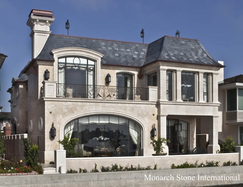 Esempio della facciata di una casa grande beige classica a due piani con rivestimento in pietra e tetto a mansarda