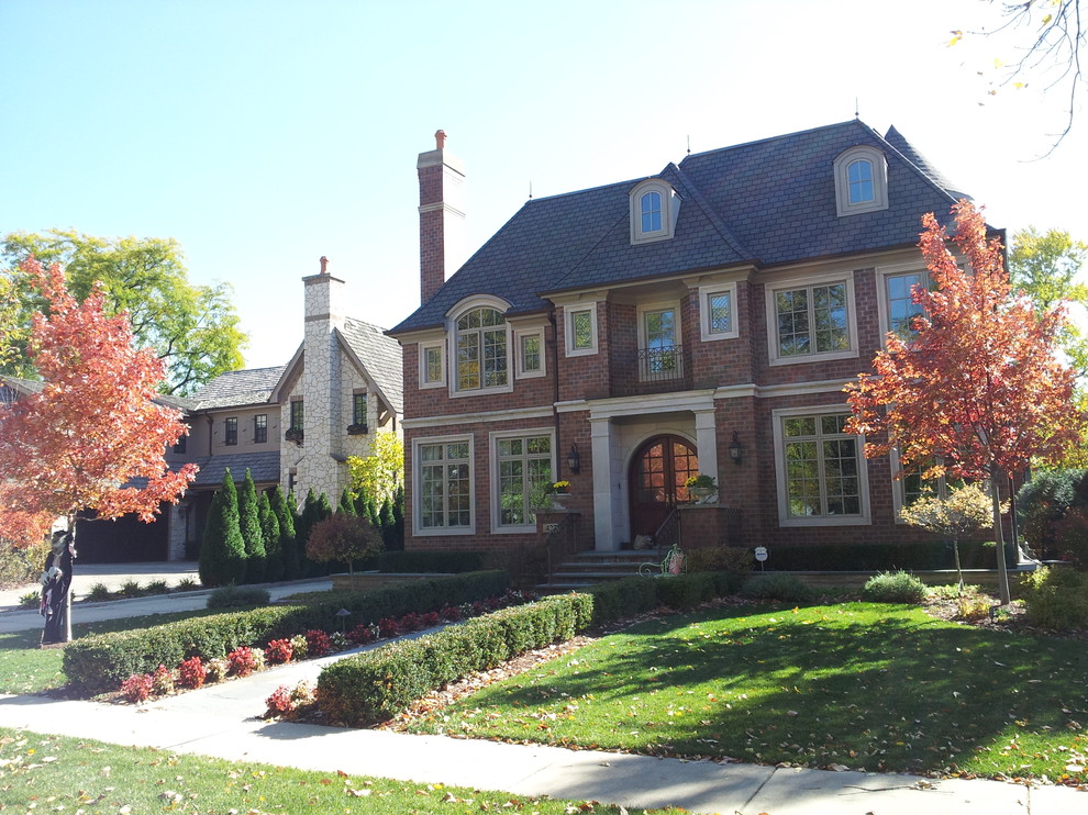 Mid-sized traditional red two-story brick house exterior idea in Chicago with a hip roof and a shingle roof