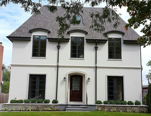 Réalisation d'une façade de maison beige tradition en stuc de taille moyenne et à un étage avec un toit à quatre pans et un toit en shingle.