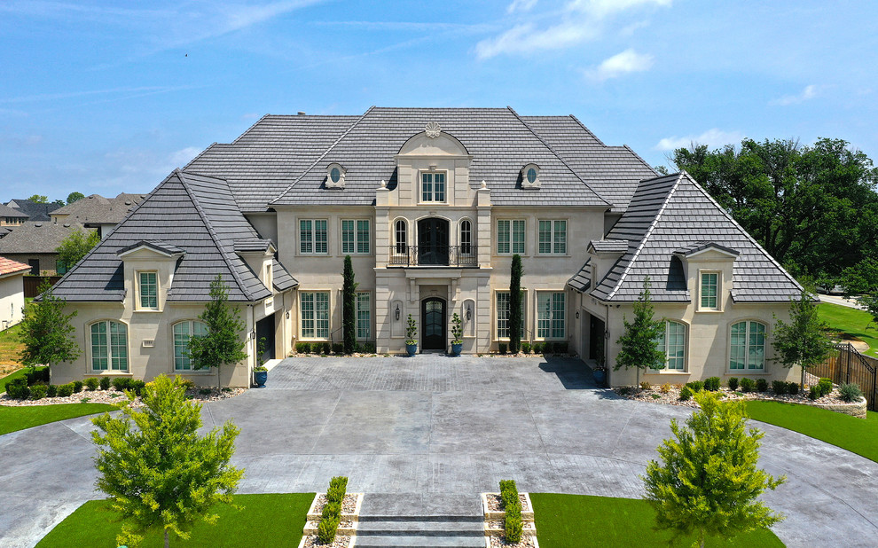 Стильный дизайн: большой, двухэтажный, бежевый частный загородный дом в классическом стиле с облицовкой из камня и черепичной крышей - последний тренд