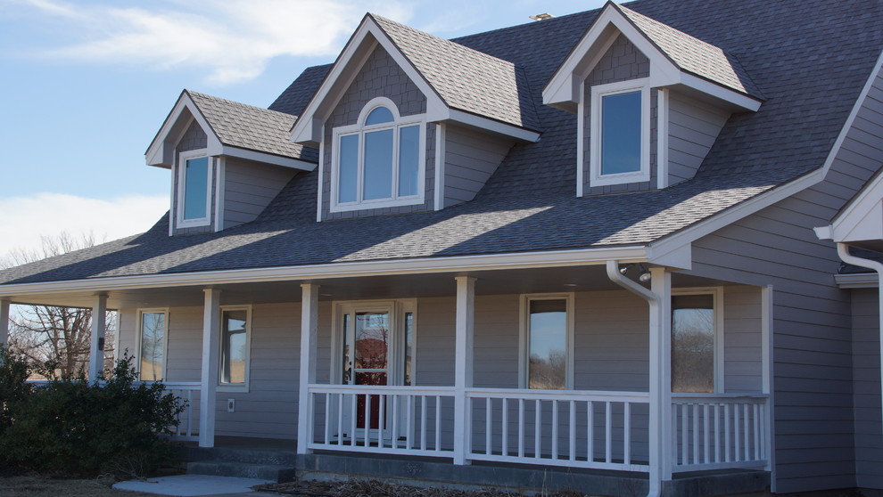 Exemple d'une façade de maison grise chic de taille moyenne et à un étage avec un revêtement en vinyle et un toit en appentis.