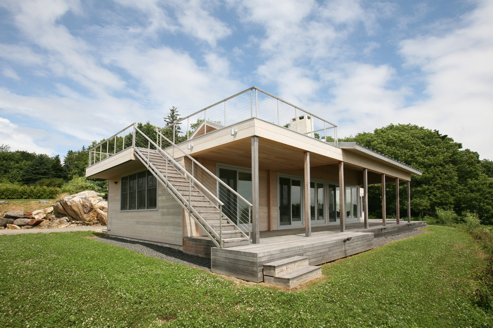 Imagen de fachada rural de dos plantas con revestimiento de madera y tejado plano
