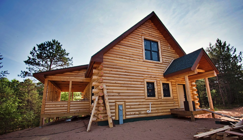 Esempio della villa marrone rustica a due piani di medie dimensioni con rivestimento in legno, tetto a capanna e copertura a scandole