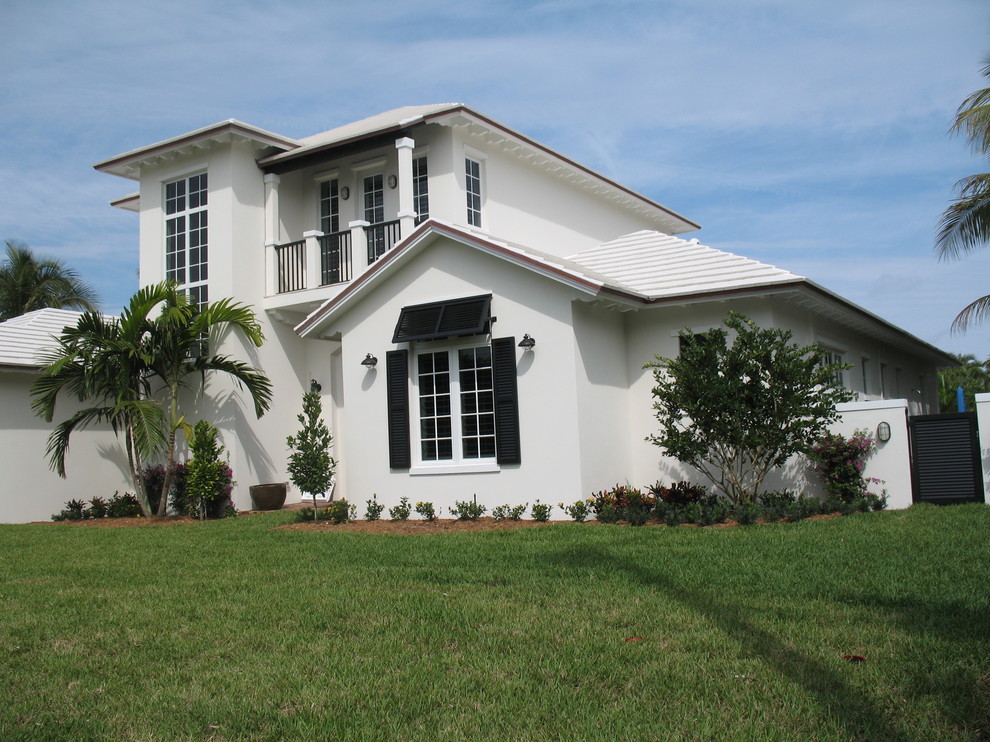 Photo of a large and white world-inspired two floor render house exterior in Miami with a mansard roof.