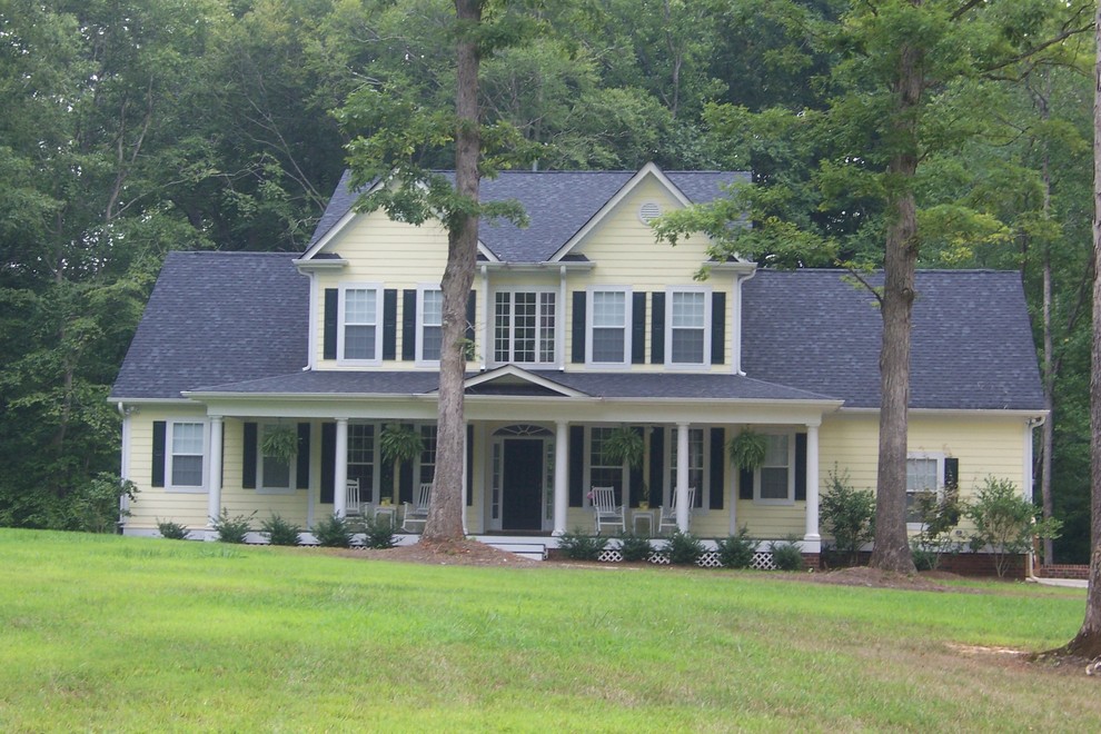 Example of a mid-sized farmhouse yellow two-story vinyl gable roof design in Charlotte