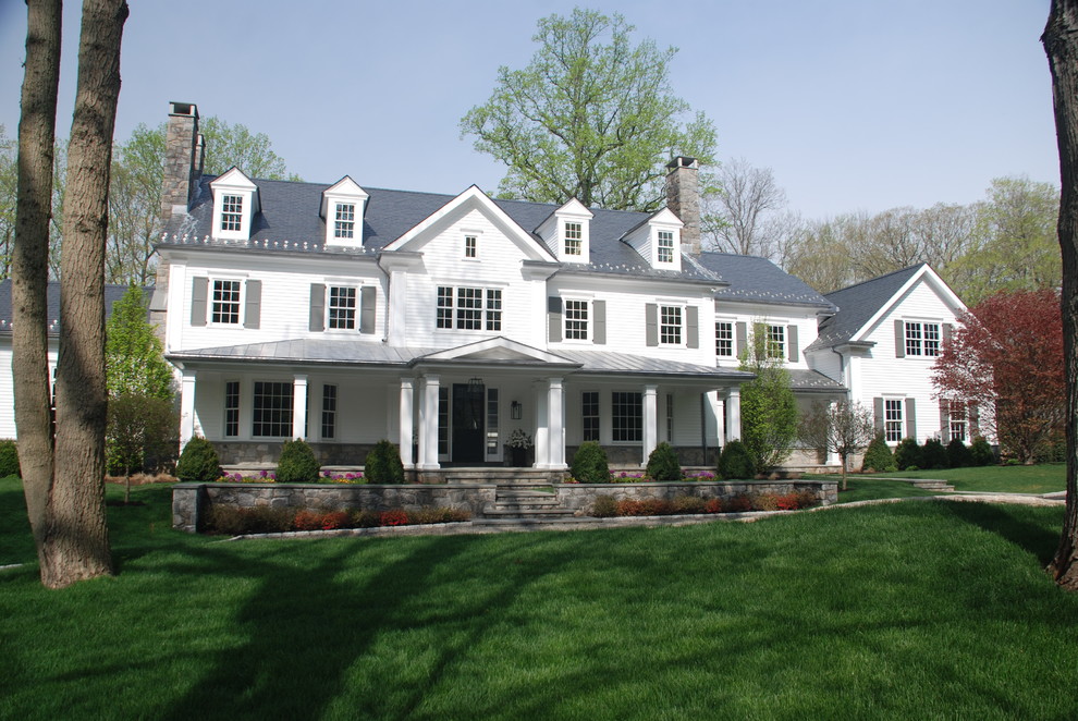 Réalisation d'une grande façade de maison blanche tradition en bois à un étage avec un toit à deux pans et un toit mixte.
