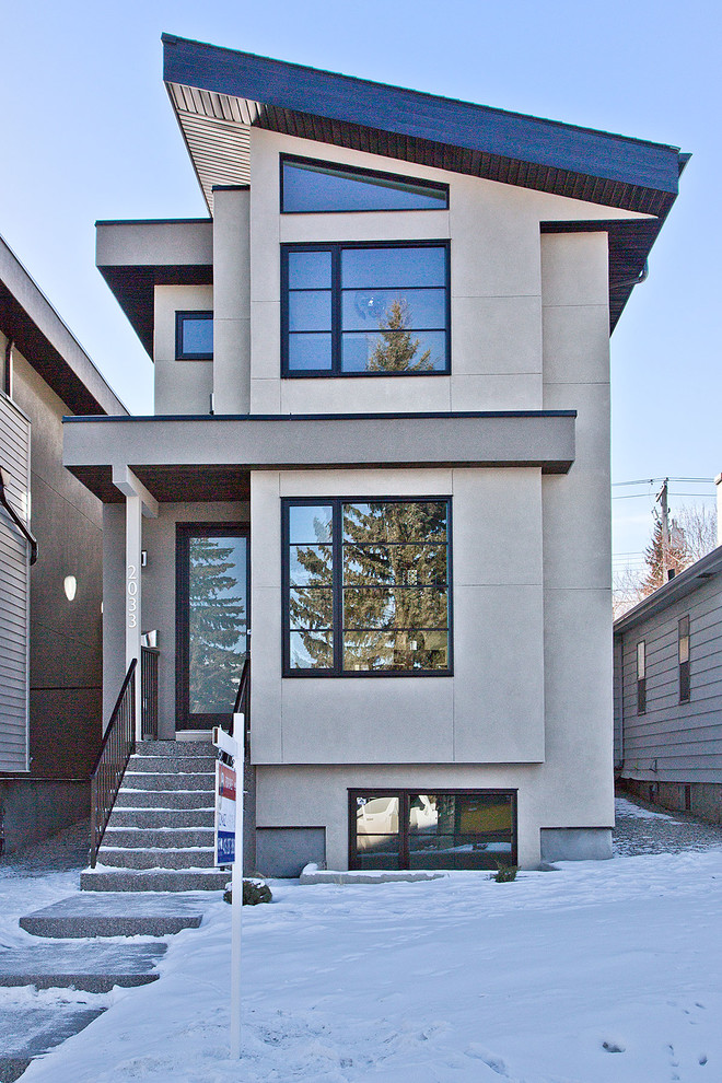 Kleines, Zweistöckiges Modernes Haus mit Putzfassade, beiger Fassadenfarbe und Pultdach in Calgary