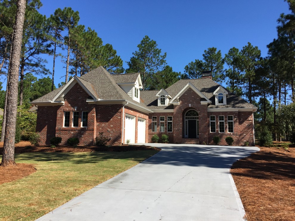Inspiration for a mid-sized timeless red two-story brick house exterior remodel in Raleigh with a hip roof and a shingle roof