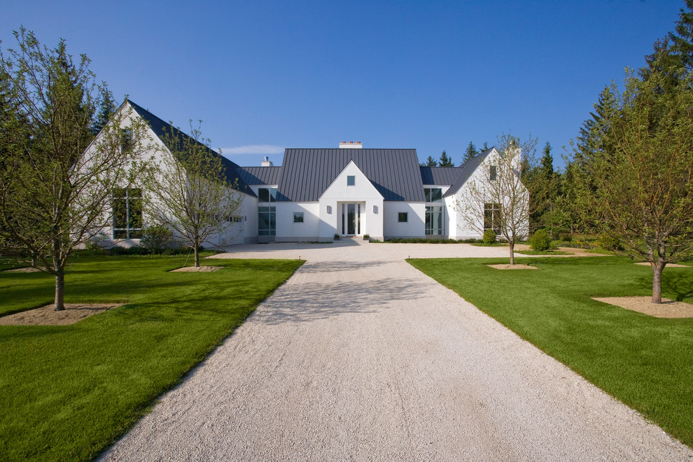 Aménagement d'une grande façade de maison blanche classique en stuc à un étage avec un toit à deux pans.