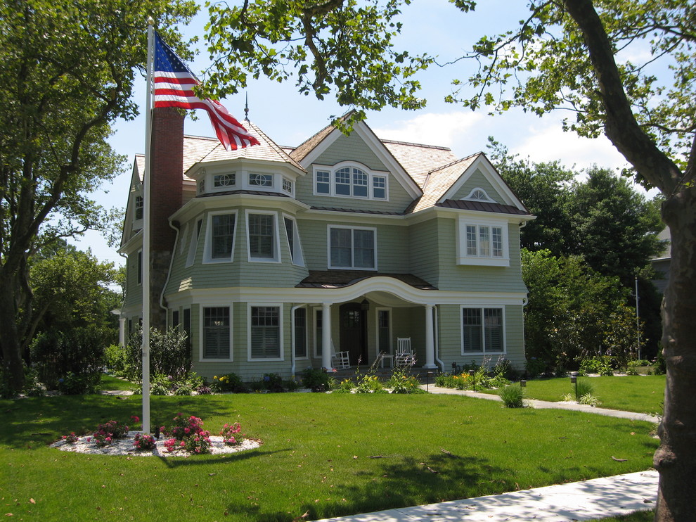 Cette image montre une très grande façade de maison verte traditionnelle en bois à deux étages et plus avec un toit à deux pans.