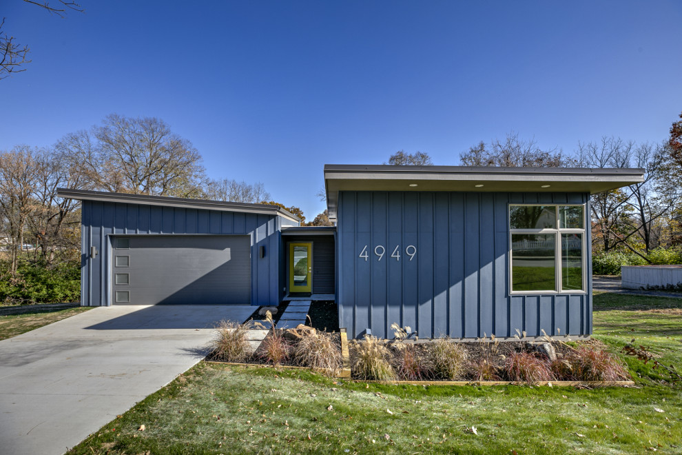 Modelo de fachada de casa azul retro de tamaño medio de dos plantas con revestimientos combinados, tejado de un solo tendido y tejado de metal