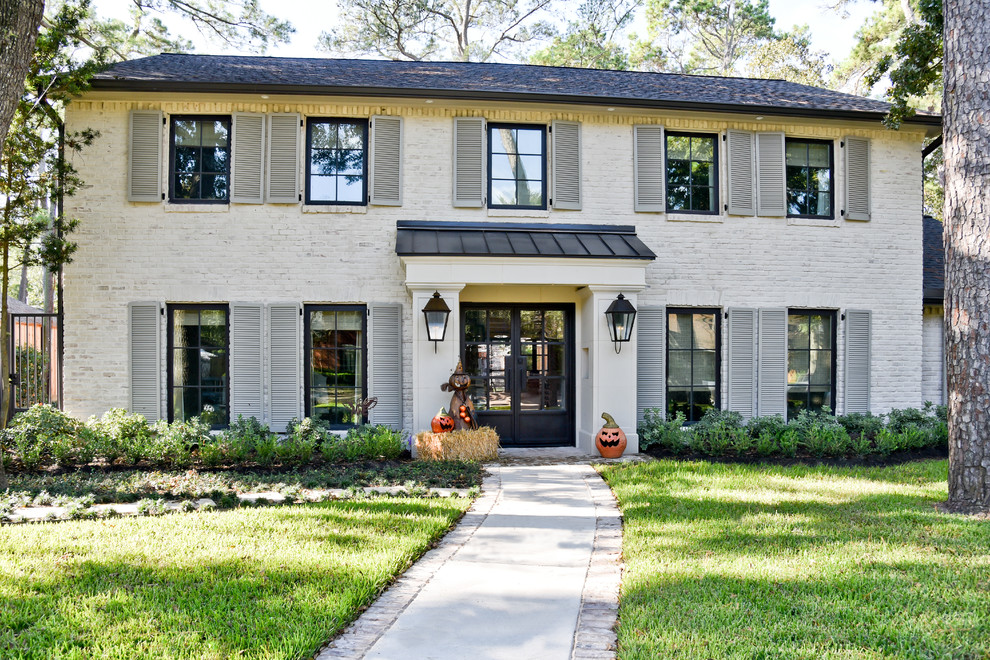 Example of a classic white two-story brick house exterior design in Houston with a shingle roof and a hip roof