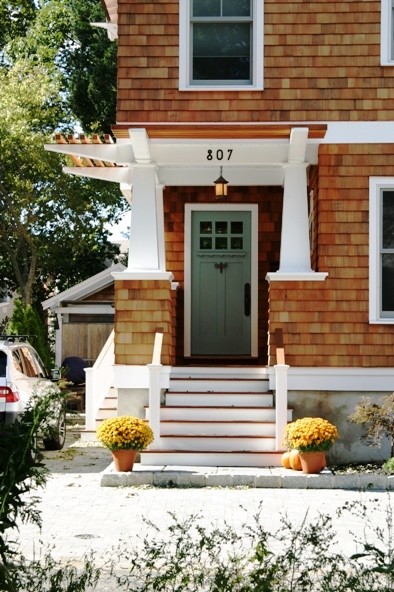 Modelo de fachada de casa marrón de estilo americano de tamaño medio de dos plantas con revestimiento de madera, tejado a dos aguas y tejado de teja de madera