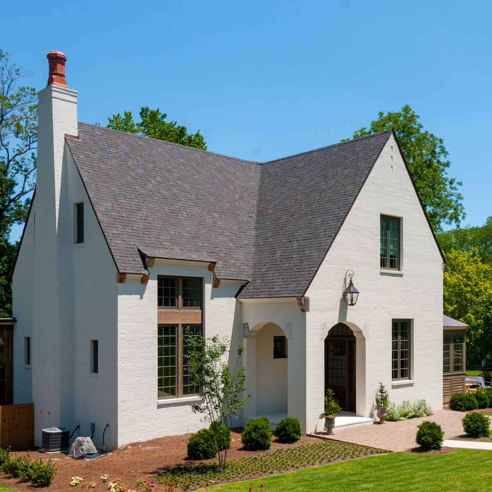 Imagen de fachada de casa blanca tradicional de tamaño medio de tres plantas con revestimientos combinados, tejado a dos aguas y tejado de teja de madera
