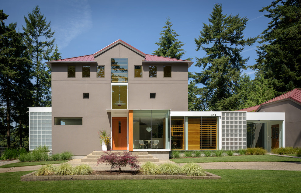 Imagen de fachada de casa gris moderna grande de tres plantas con revestimiento de estuco, tejado a cuatro aguas y tejado de metal