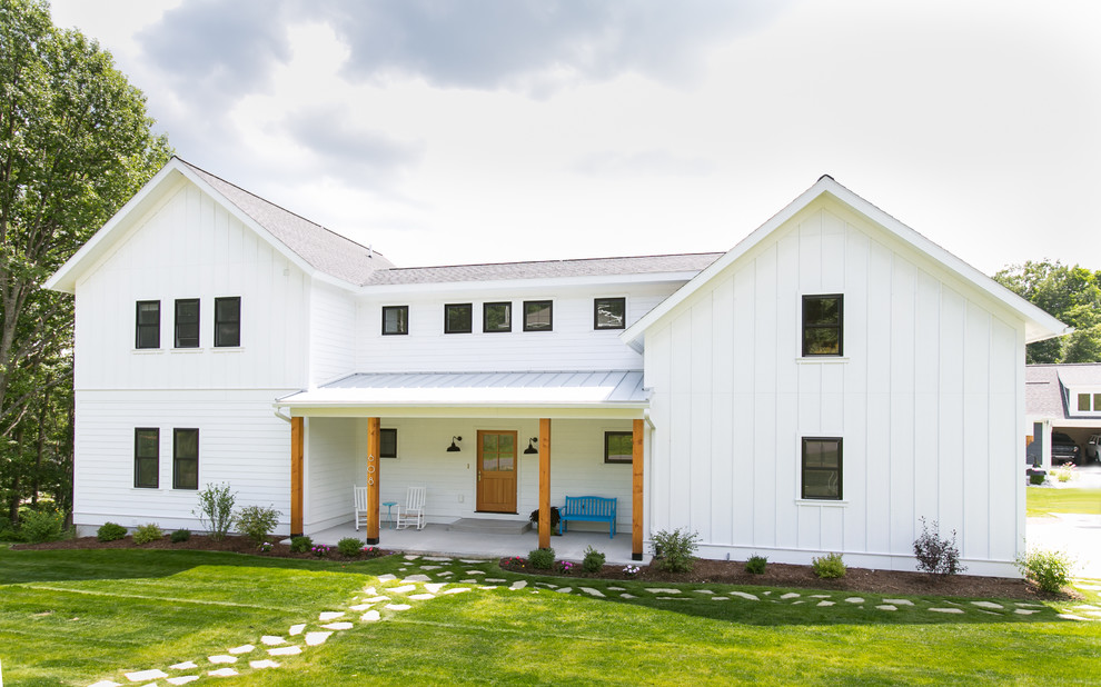 Modelo de fachada blanca de estilo de casa de campo de tamaño medio de tres plantas con revestimientos combinados y tejado a dos aguas