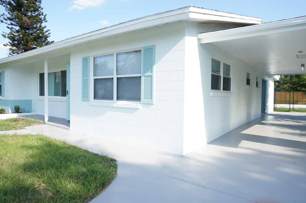 This is an example of a medium sized and white retro bungalow concrete house exterior in Orlando with a pitched roof and a shingle roof.
