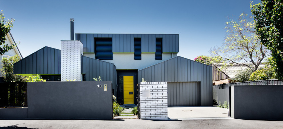 Cette image montre une grande façade de maison grise et métallique minimaliste à un étage avec un toit à quatre pans et un toit en métal.